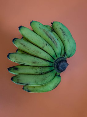 Havuç sarısı arka planda olgun yeşil muzlar.