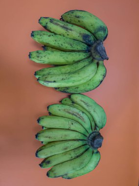 Havuç sarısı arka planda olgun yeşil muzlar.