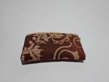 Kadın cüzdanı desenli kahverengi kumaştan yapılmış.