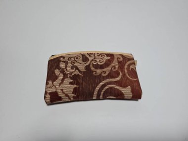 Kadın cüzdanı desenli kahverengi kumaştan yapılmış.