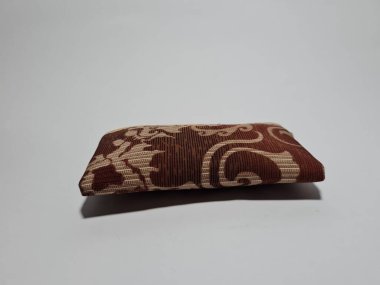 Kadın cüzdanı desenli kahverengi kumaştan yapılmış.