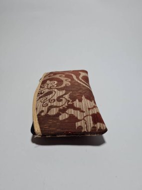 Kadın cüzdanı desenli kahverengi kumaştan yapılmış.