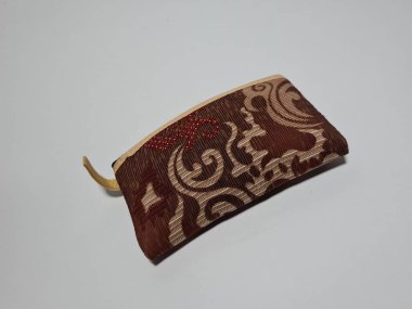 Kadın cüzdanı desenli kahverengi kumaştan yapılmış.