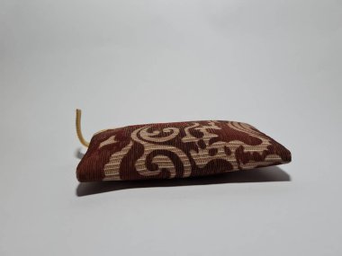 Kadın cüzdanı desenli kahverengi kumaştan yapılmış.