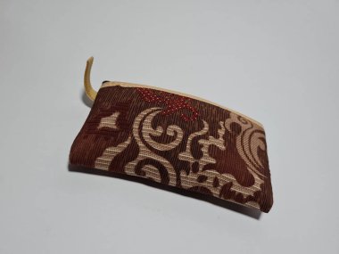 Kadın cüzdanı desenli kahverengi kumaştan yapılmış.