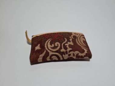 Kadın cüzdanı desenli kahverengi kumaştan yapılmış.