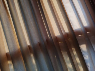 Abstract background textured brown window curtains exposed to sunlight so that shadows appear