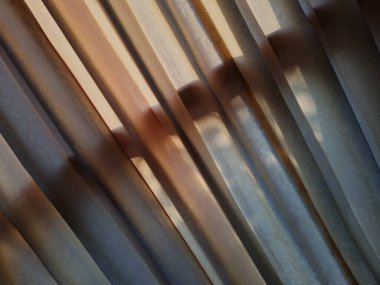 Abstract background textured brown window curtains exposed to sunlight so that shadows appear