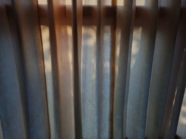 Abstract background textured brown window curtains exposed to sunlight so that shadows appear
