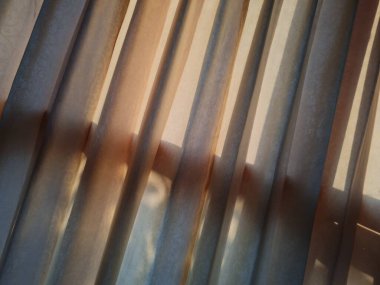 Abstract background textured brown window curtains exposed to sunlight so that shadows appear