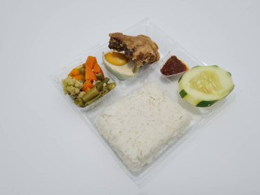 A dish consisting of white rice with side dishes, fried chicken, salted egg, capcay vegetables and sliced cucumber