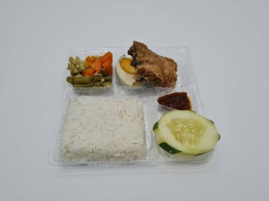 A dish consisting of white rice with side dishes, fried chicken, salted egg, capcay vegetables and sliced cucumber