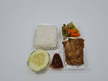 A dish consisting of white rice with side dishes, fried chicken, salted egg, capcay vegetables and sliced cucumber