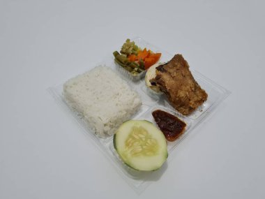 A dish consisting of white rice with side dishes, fried chicken, salted egg, capcay vegetables and sliced cucumber