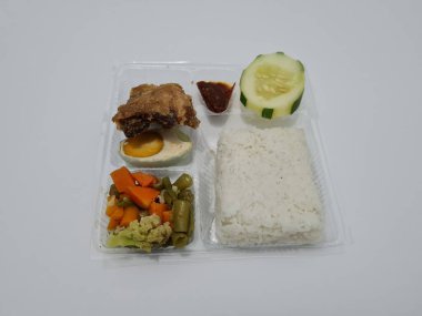 A dish consisting of white rice with side dishes, fried chicken, salted egg, capcay vegetables and sliced cucumber
