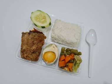 A dish consisting of white rice with side dishes, fried chicken, salted egg, capcay vegetables and sliced cucumber