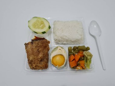 A dish consisting of white rice with side dishes, fried chicken, salted egg, capcay vegetables and sliced cucumber