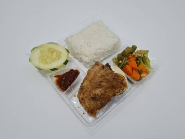 A dish consisting of white rice with side dishes, fried chicken, salted egg, capcay vegetables and sliced cucumber