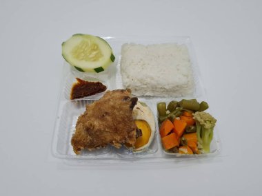 A dish consisting of white rice with side dishes, fried chicken, salted egg, capcay vegetables and sliced cucumber