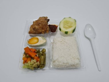 A dish consisting of white rice with side dishes, fried chicken, salted egg, capcay vegetables and sliced cucumber