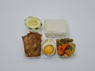 A dish consisting of white rice with side dishes, fried chicken, salted egg, capcay vegetables and sliced cucumber
