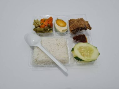 A dish consisting of white rice with side dishes, fried chicken, salted egg, capcay vegetables and sliced cucumber