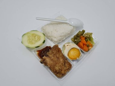 A dish consisting of white rice with side dishes, fried chicken, salted egg, capcay vegetables and sliced cucumber