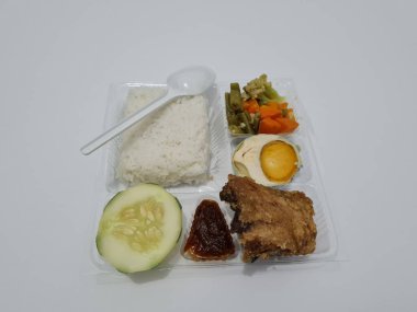 A dish consisting of white rice with side dishes, fried chicken, salted egg, capcay vegetables and sliced cucumber