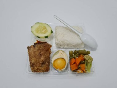 A dish consisting of white rice with side dishes, fried chicken, salted egg, capcay vegetables and sliced cucumber