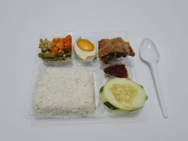 A dish consisting of white rice with side dishes, fried chicken, salted egg, capcay vegetables and sliced cucumber