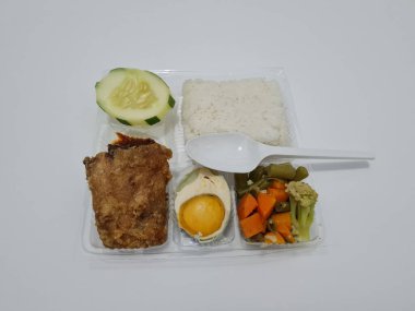 A dish consisting of white rice with side dishes, fried chicken, salted egg, capcay vegetables and sliced cucumber