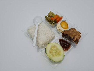 A dish consisting of white rice with side dishes, fried chicken, salted egg, capcay vegetables and sliced cucumber