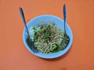 A dish called dumplings, which contains noodles with vegetables plus a pentol in a bowl