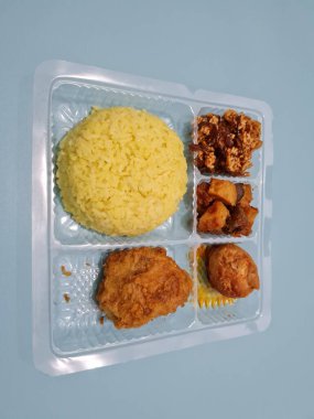 Yellow rice with fried chicken, fried noodles, fried chili and others