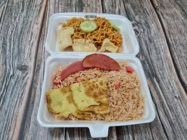 Kızarmış erişteli pilav, kızarmış yumurta, sosis dilimleri ve salatalık dilimleri.