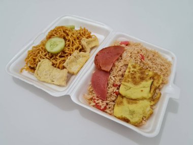 Kızarmış erişteli pilav, kızarmış yumurta, sosis dilimleri ve salatalık dilimleri.