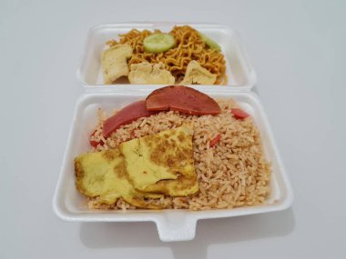 Kızarmış erişteli pilav, kızarmış yumurta, sosis dilimleri ve salatalık dilimleri.