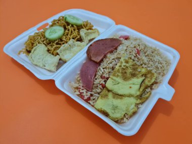 Kızarmış erişteli pilav, kızarmış yumurta, sosis dilimleri ve salatalık dilimleri.