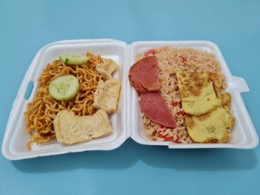 Kızarmış erişteli pilav, kızarmış yumurta, sosis dilimleri ve salatalık dilimleri.