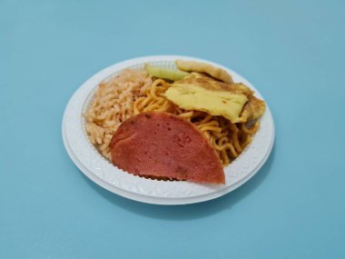 Kızarmış erişteli pilav, kızarmış yumurta, sosis dilimleri ve salatalık dilimleri.