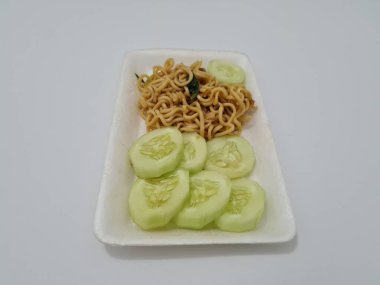 Beyaz bir kabın içinde salatalık dilimli kızarmış erişte.