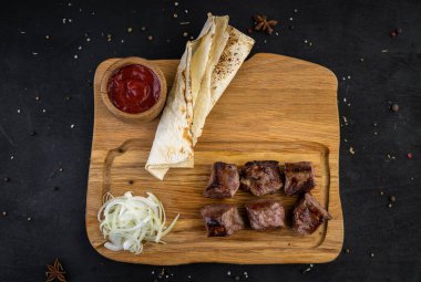 Tahtada kızarmış domuz kebabı, ekmek ve sosla birlikte.