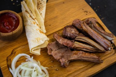 Baharatlı kızarmış domuz pirzolası, ekmek ve ketçaplı.