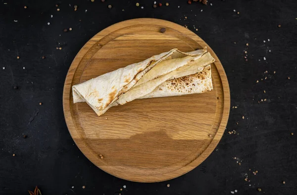  Siyah arka planda tahta üzerinde kızarmış pita ekmeği.