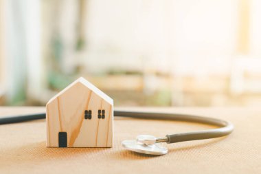 Ev onarımı ve müfettiş konsepti. Stetoskop ve ahşap ev modeli. Ev ve emlakları gün ışığıyla kontrol ediyorum..