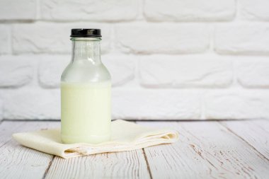 Beyaz masa örtüsüne bir şişe taze süt. Mutfakta duvarda metnin için fotokopi alanı var. Yüksek kalsiyum ve vitaminler. Sabah için iyi bir içecek..