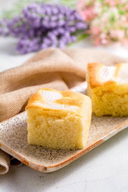 Tabakta kare hindistan cevizli kek ve beyaz masa. Ev yapımı lezzetli fırın.. 