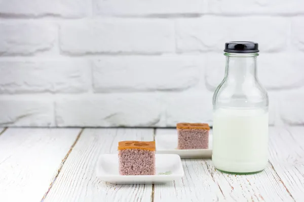 キッチンの白いプレートの上にスイートポテトケーキの正方形のカットで提供される新鮮な牛乳のボトル ベーカリー 飲料のコンセプト — ストック写真