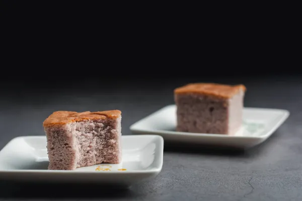 A square-cut of sweet potato cake on a white plate in the kitchen. Bakery and beverage concept.