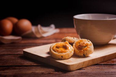 Ahşap doğrama tahtasının üzerinde kaju fıstığı ve siyah deniz kabuğu kurabiyeleri. Ahşap masada bir fincan kahveyle servis ediliyor. Kahve saati için nefis atıştırmalıklar..